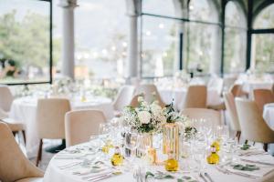 布里萨戈Hotel Villa Emden的一张桌子,用来举办婚礼,上面有白色的桌子和椅子