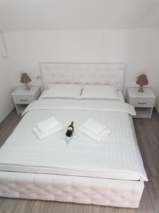 阿尔杰什河畔库尔泰亚Casa Sima的一张白色的床,上面有一瓶葡萄酒