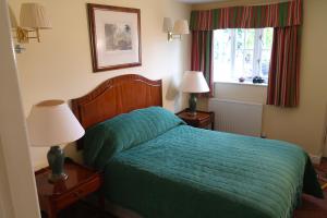 Branston敦斯顿红狮子宾馆的一间卧室配有一张带绿色被子的床和两盏灯。
