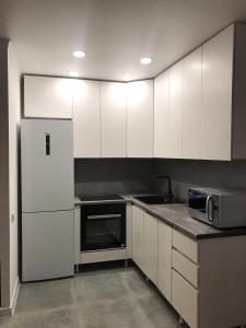 阿拉木图Стильная однокомнатная квартира в г.Алматы的厨房配有白色橱柜、水槽和冰箱。