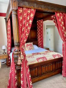 坎特伯雷Canterbury Hotel Cottages and Apartment's的卧室内的一张带红色窗帘的天蓬床