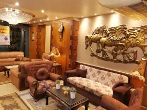 Banī ‘AţīyahCity Center Hotel Beni Suef的客厅配有沙发,墙上有马匹