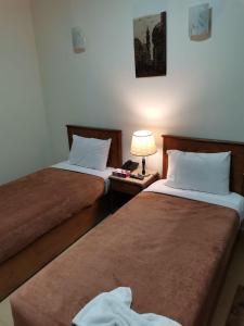 Banī ‘AţīyahCity Center Hotel Beni Suef的酒店客房设有两张床和一张桌子上的台灯。