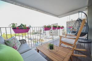 提比里亚YalaRent Migdalor Boutique Hotel Apartments with Sea Views Tiberias的阳台配有沙发、秋千和一些植物