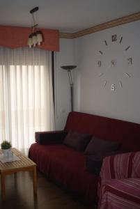 La Puebla de CastroApartamento VUT manypi VU-HUESCA-21-024的客厅配有红色的沙发和墙上的时钟