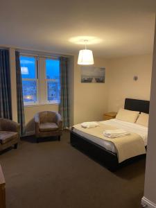 邓巴Hillside Bed & Breakfast Dunbar的一间卧室配有一张床、一把椅子和窗户。