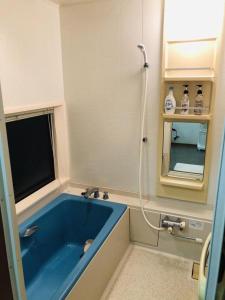 富士河口湖コテージトガワ＜Cottage TOGAWA＞的浴室设有蓝色浴缸和镜子