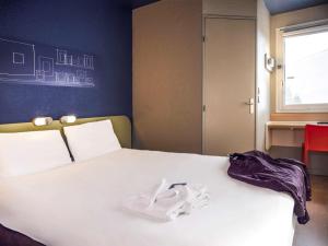 阿尔勒阿尔勒南富尔雄宜必思经济酒店的一间卧室,床上有白色的衣服