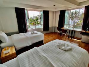 帕夭Baan Arunothai Homestay的酒店客房设有两张床、一张书桌和窗户。