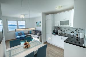 伊格拉恩Apartman Nimfa的厨房以及带白色橱柜和桌子的客厅。