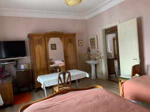 圣阿玛尼Chambre Gentiane 2 à 3 personnes wifi sdb partagée的一间卧室配有一张床、一张桌子和一台电视。