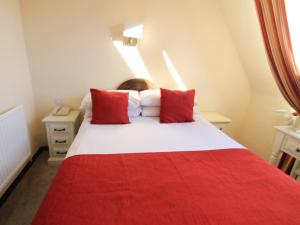 坎特伯雷清教徒酒店的卧室配有红色和白色的床和红色枕头