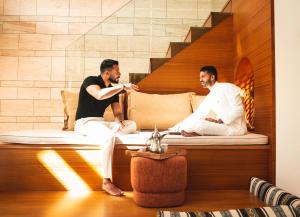吉达SHIRVAN Hotel City Yard Jeddah的两个人坐在房间里的床边