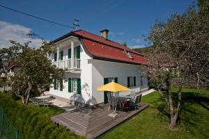 沃尔特湖畔佩莎赫Ferienhaus Kleine Gartenvilla的白色的房子,有甲板和黄色的伞
