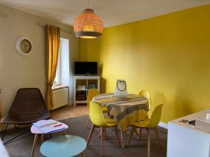 格朗维尔L'escale Granvillaise的用餐室设有黄色的墙壁和桌椅