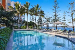 黄金海岸布罗德沃特银色海岸公寓酒店的一个带椅子和棕榈树的度假村游泳池