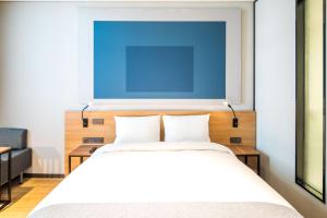 水原市宜必思水原大使酒店的一间卧室配有一张挂着蓝色画作的床铺。