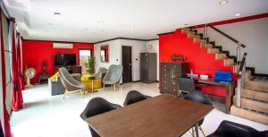 北芭堤雅4普尔维拉斯度假屋的客厅设有红色的墙壁和桌椅