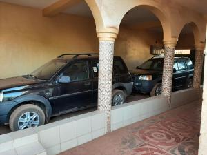巴马科Appartement chambre salon climatisées, cuisine的两辆汽车停在一个有柱子的停车场