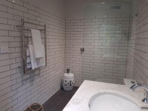 克拉佛斯Mt Lofty Botanic Garden Studio的白色瓷砖浴室设有水槽和毛巾