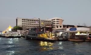 曼谷Sabai Sabai Liveaboard Bangkok的一群船停靠在河里,有建筑物