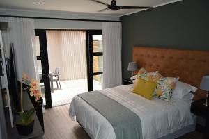 约翰内斯堡The Guesthouse 6 on Vrede的一间卧室配有一张带黄色枕头的床和一个阳台