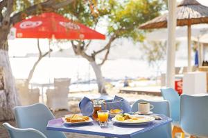 卡尔帕索斯MINOS BEACH KARPATHoS的一张蓝色桌子,上面放着食物盘子和红伞
