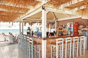 卡尔帕索斯MINOS BEACH KARPATHoS的海滩上的餐厅,设有酒吧及椅子