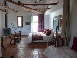 Mondújar德拉巴卡旅馆的一间卧室设有两张床、一张桌子和一个壁炉
