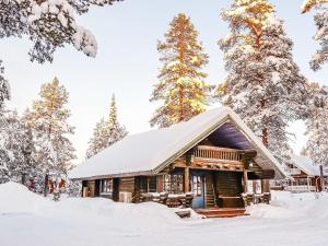 列维Holiday Home Tikkatupa by Interhome的雪中树下的小木屋