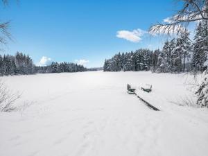 Juhanala瓦特拉卡维洛玛克斯库度假屋的两长椅,在雪覆盖的田野上,种着树木