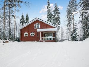 Juhanala瓦特拉卡维洛玛克斯库度假屋的雪中小红房子,有树