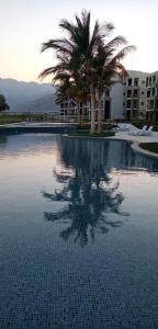 希法Studio Jebel Sifah Resort Golf Lake G 14 - 201的一座棕榈树游泳池和一座建筑