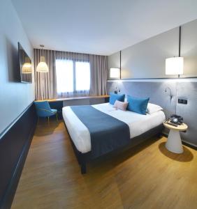 里昂Hôtel Le Roosevelt Lyon的酒店客房配有一张带蓝色枕头的大床