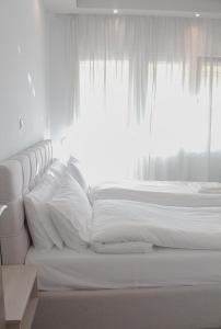 兹拉马Apartment Ori的白色的床、白色枕头和窗户