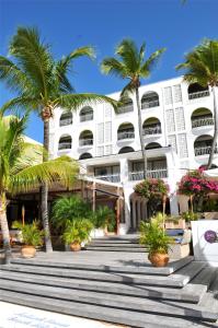 菲利普斯堡荷兰屋海滩酒店的一座白色的建筑,前面有棕榈树