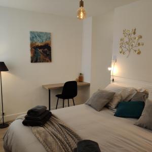孔卡尔诺LE 21 Vue sur Mer的一间卧室配有一张带书桌和绘画的床。