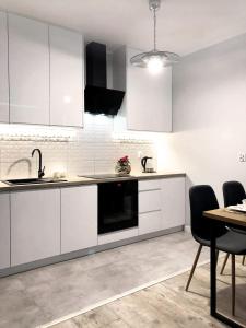 埃尔布隆格Apartament Stare Miasto的厨房配有白色橱柜和桌椅