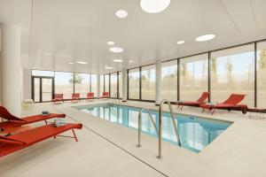 鲁瓦西昂法兰西Hyatt Place Paris Charles de Gaulle Airport的一个带红色椅子的大型游泳池和一个游泳池