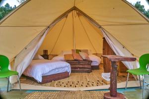 莱瓦镇Glampwild Zaquencipa的帐篷配有一张床和一张桌子及椅子