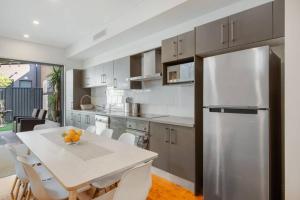 悉尼BRID243FL - The Terrace on Bridge的厨房配有白色桌子和不锈钢冰箱。