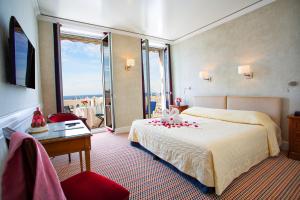 戛纳斯普兰迪德酒店的配有一张床、一张书桌和一扇窗户的酒店客房