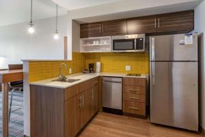 卡尔斯巴德MainStay Suites Carlsbad South的厨房配有木制橱柜和不锈钢冰箱。