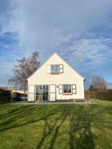 ZillebekeVakantiehuis Cas.tard的坐落在郁郁葱葱的绿色田野顶部的白色房子