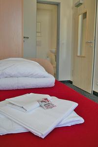 柏林CVJM Jugendgästehaus Berlin的红色床上一双白色毛巾