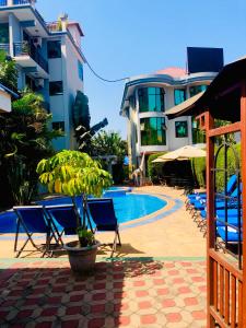 阿鲁沙绿山酒店 的一座带椅子和树的游泳池,毗邻一座建筑