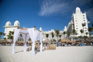 棕榈滩Riu Palace Aruba - All Inclusive的一个带帐篷和椅子的海滩和一座建筑