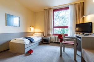 巴登-巴登Hotel Baden-Baden的一间卧室配有一张床、一张书桌和一台电视