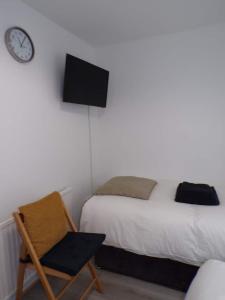 滨海绍森德City Beach AirBnB Southend on Sea,的一间卧室配有一张床、一把椅子和闹钟