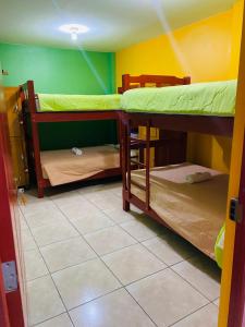 利马Sunset Hostel Airport的客房设有两张双层床,铺有瓷砖地板。